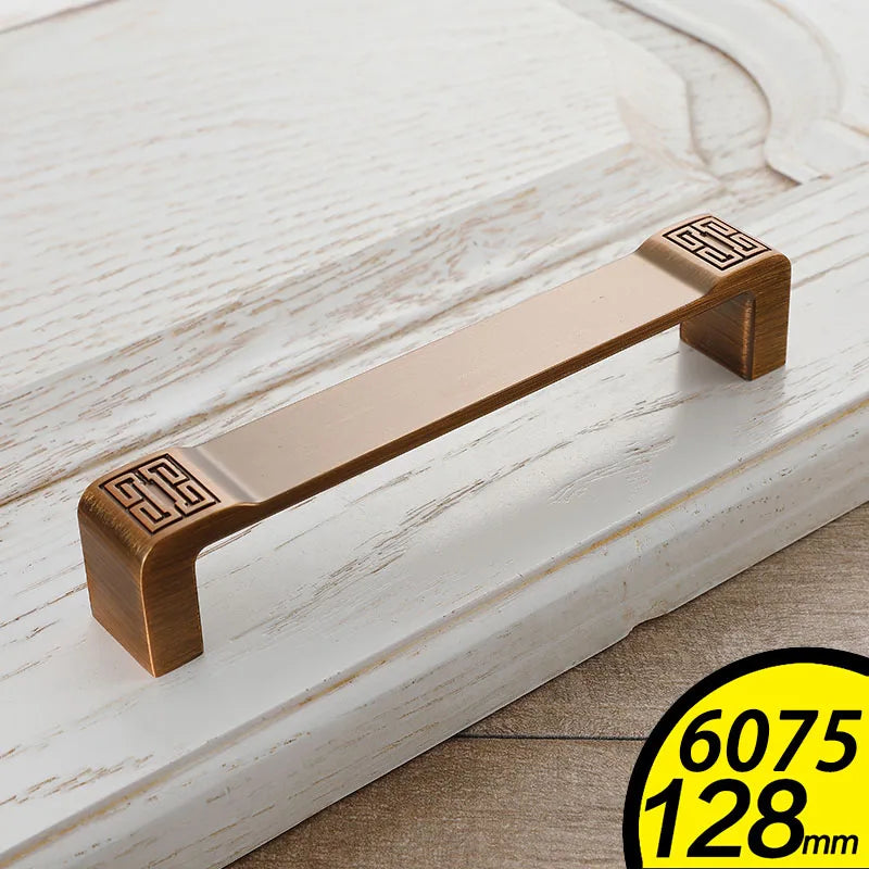 Vintage Cabinet Handles in bronze finish with decorative square patterns on white wood drawer