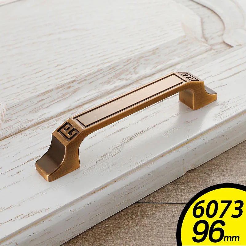 Antique bronze vintage cabinet handles with decorative engraved ends on white wooden drawer