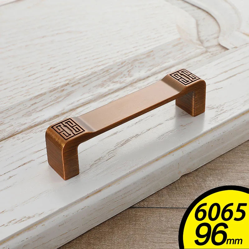 Antique bronze vintage cabinet handles with decorative square engravings on white wood drawer