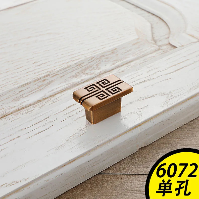 Antique bronze vintage cabinet handles with geometric design on white distressed wooden drawer
