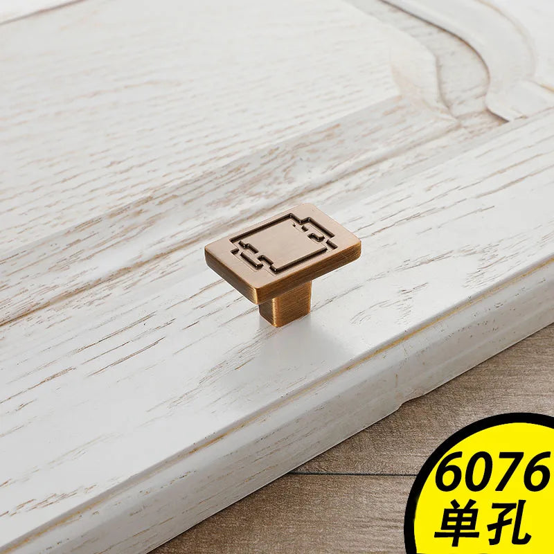 Square bronze vintage cabinet handles with geometric design on distressed white wood drawer