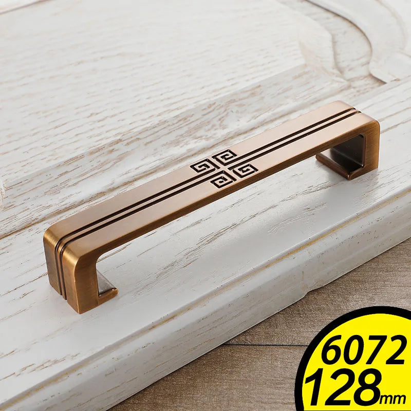 Bronze Vintage Cabinet Handles with intricate black design on white distressed wooden cabinet