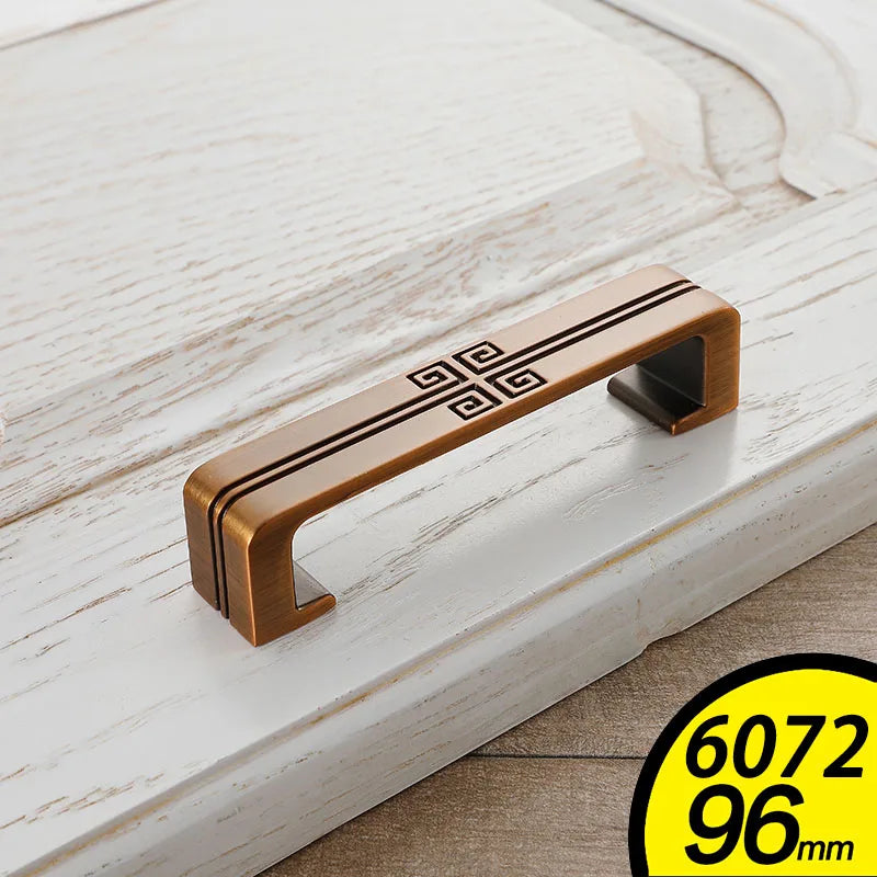 Bronze vintage cabinet handles with black geometric design on white wooden drawer