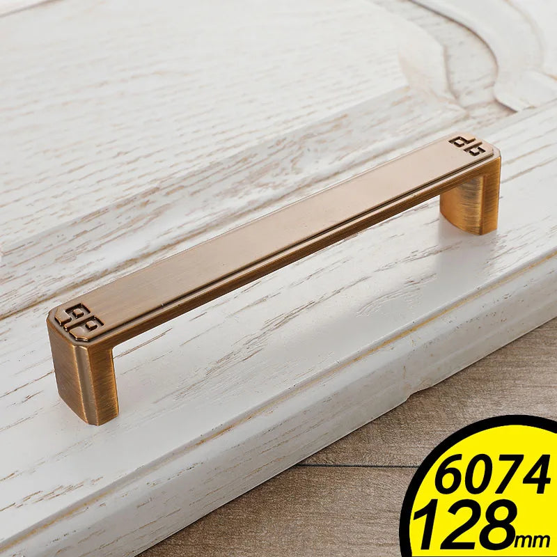 Antique brass vintage cabinet handles with decorative corner details on white wooden drawer