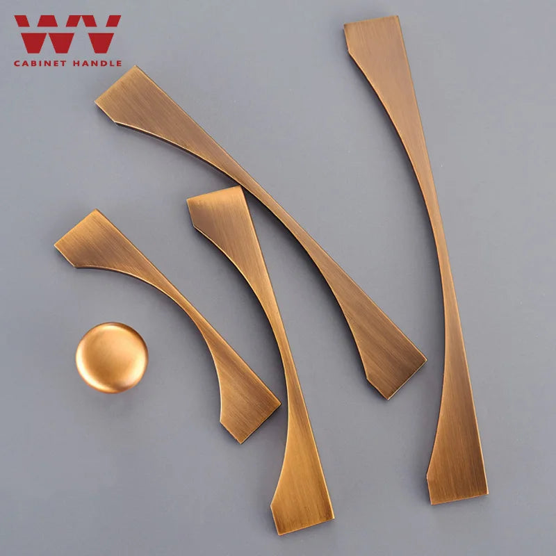 Antique brass cabinet handles and knob set with curved design on a gray background.