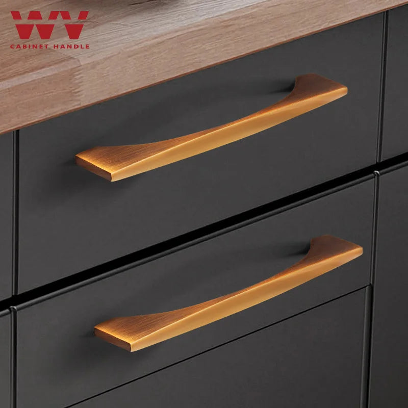 Brass cabinet handles on a matte black drawer with a wooden countertop, ideal for kitchen or wardrobe furniture.