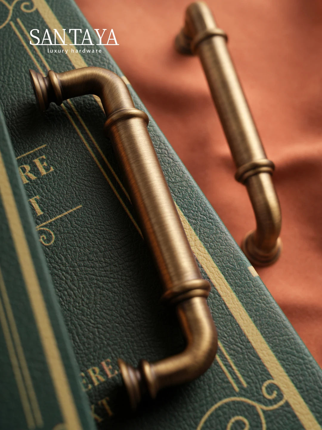 Antique brass drawer pulls with bronze finish on textured green books with warm background