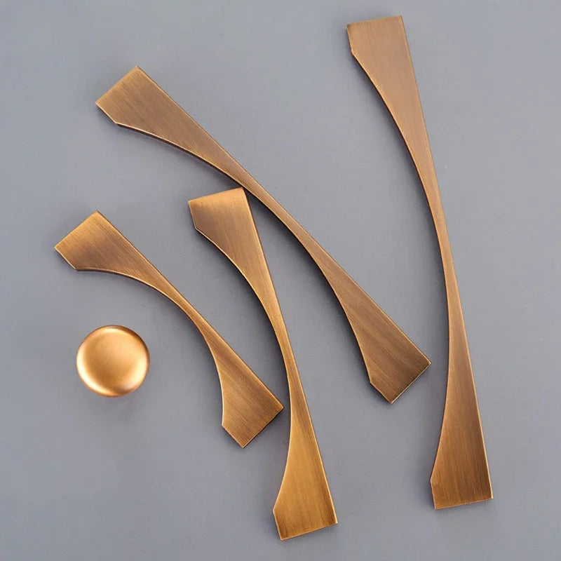 Classical antique cabinet handles and knobs in brass with a yellow bronze finish, displayed on a gray background.