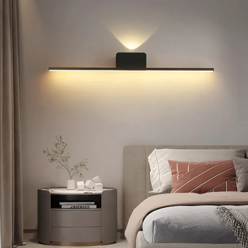 Modern minimalist LED wall lamp above a bedside setup with warm ambient lighting.