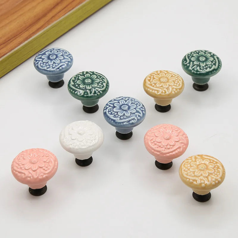 Set of vintage ceramic drawer knobs with floral design in blue, green, gold, pink, and white on a white background.