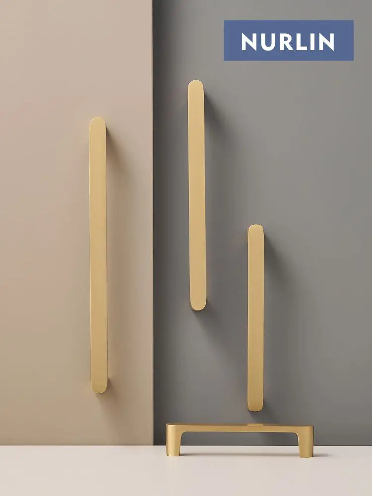 Nurlin solid brass gold cabinet door handles with simple style, shown in various orientations against a two-tone background.