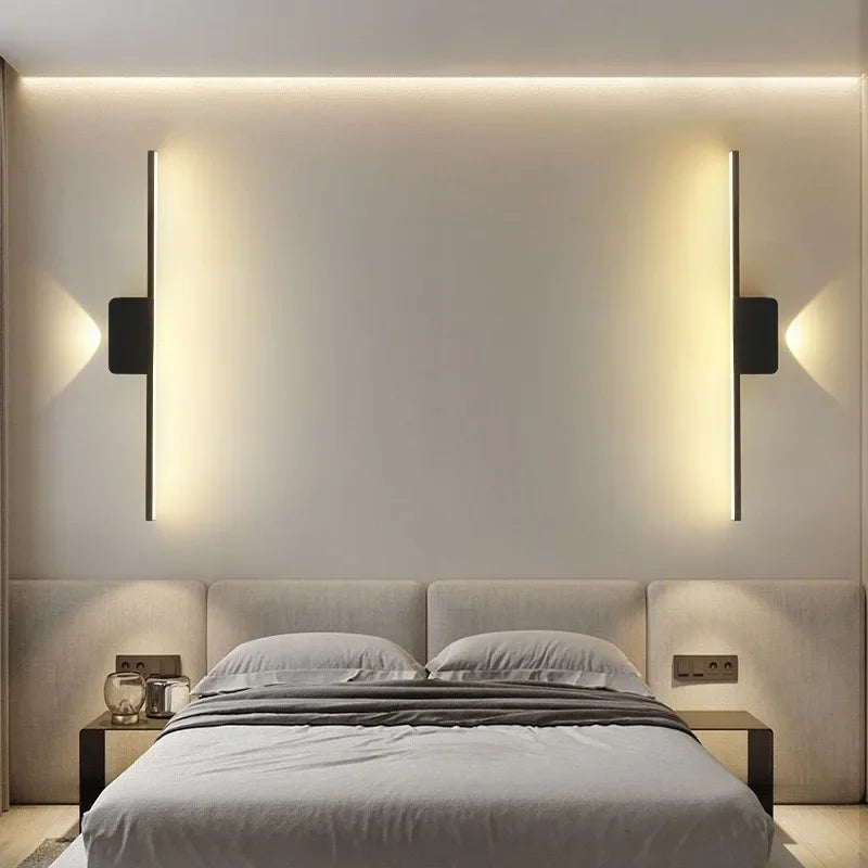 Modern minimalist LED wall lamps in a bedroom setting, featuring long strip sconces with ambient lighting on either side of a bed.