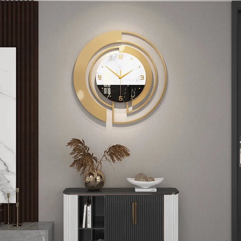 Modern wall clock with gold and black concentric circles and a marble pattern in a stylish living room setting.