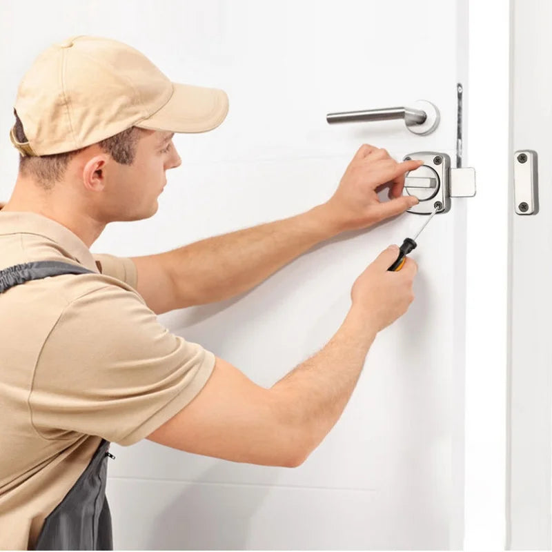 Person installing a double-sided stainless steel cabinet lock with a rotate bolt and twist rotating barrel lock on a white door.