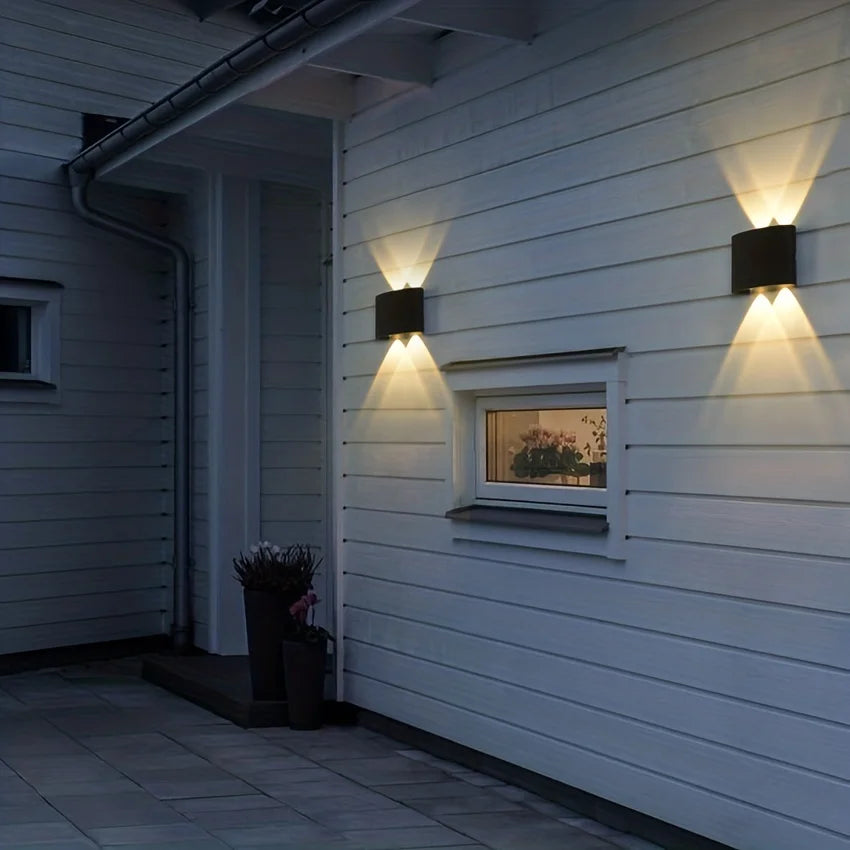 Outdoor LED wall lamps on a house exterior, emitting warm light; waterproof IP66, 4W for garden or indoor use.