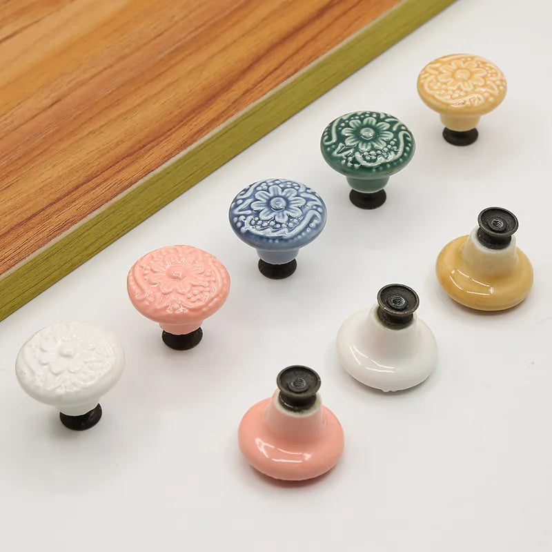 Vintage ceramic drawer knobs with floral design in various colors including blue, green, pink, yellow, and white, displayed on a light surface.