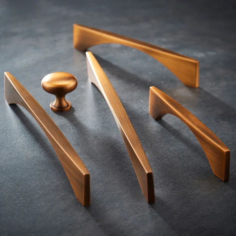 Classical antique cabinet handles and knobs in brass with yellow bronze finish on a dark surface.