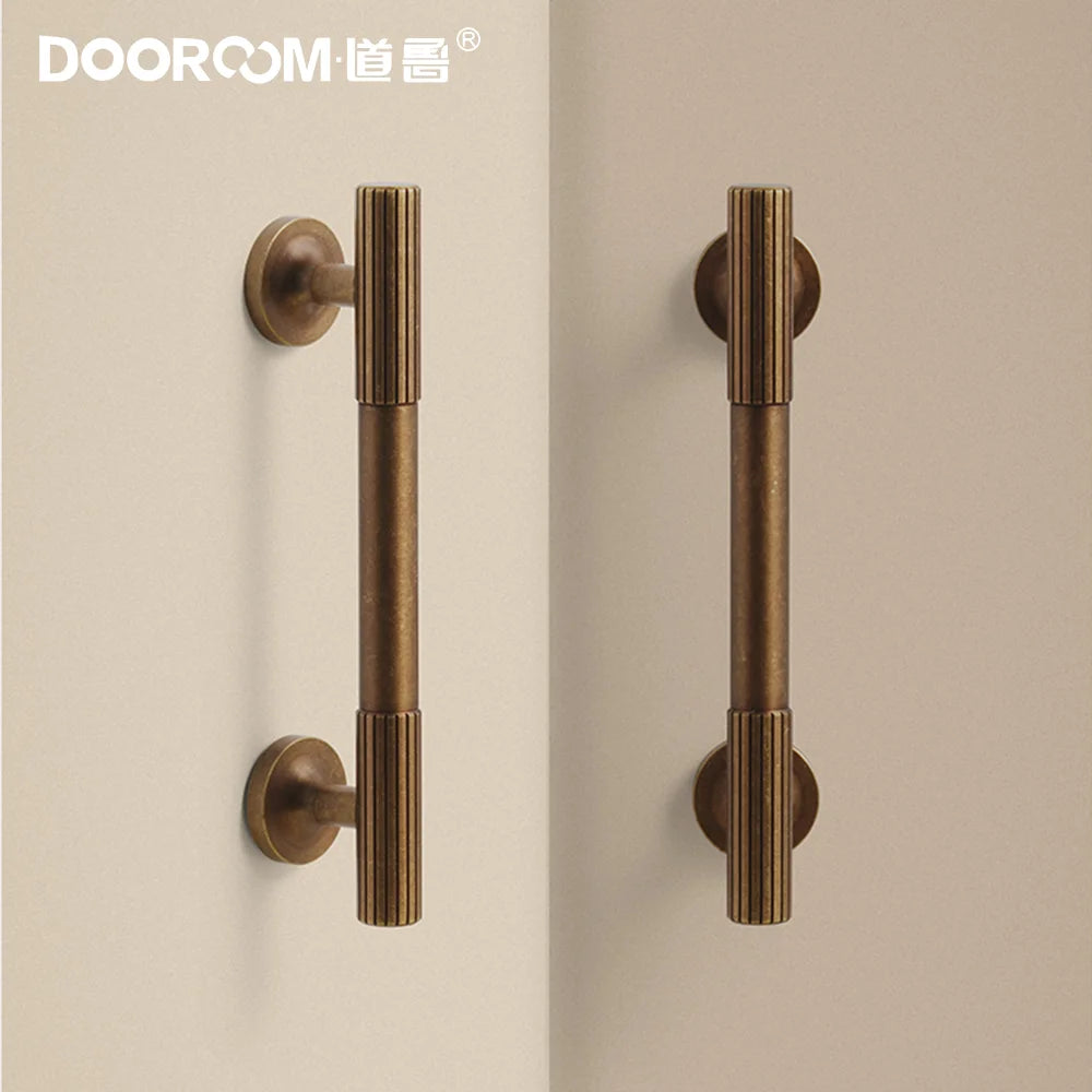 Dooroom vintage brass furniture handles with ribbed ends on cream background.