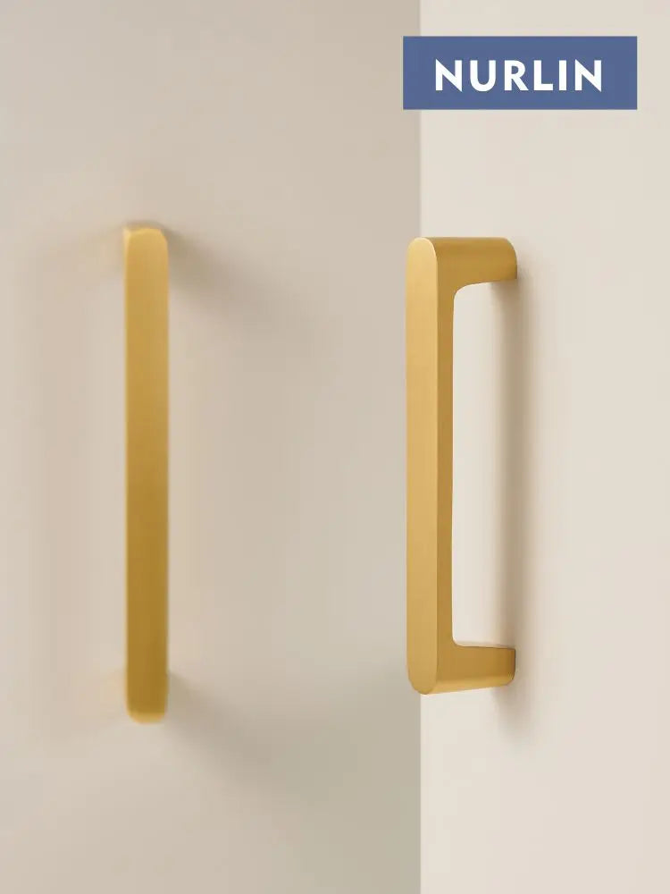 Nurlin solid brass gold handles with a modern design, shown mounted on a light surface.
