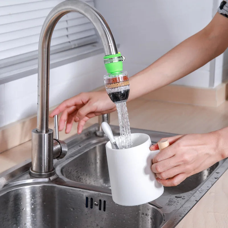 6-layer water filter with medical stone and coconut charcoal attached to a kitchen faucet, filtering water into a white mug.
