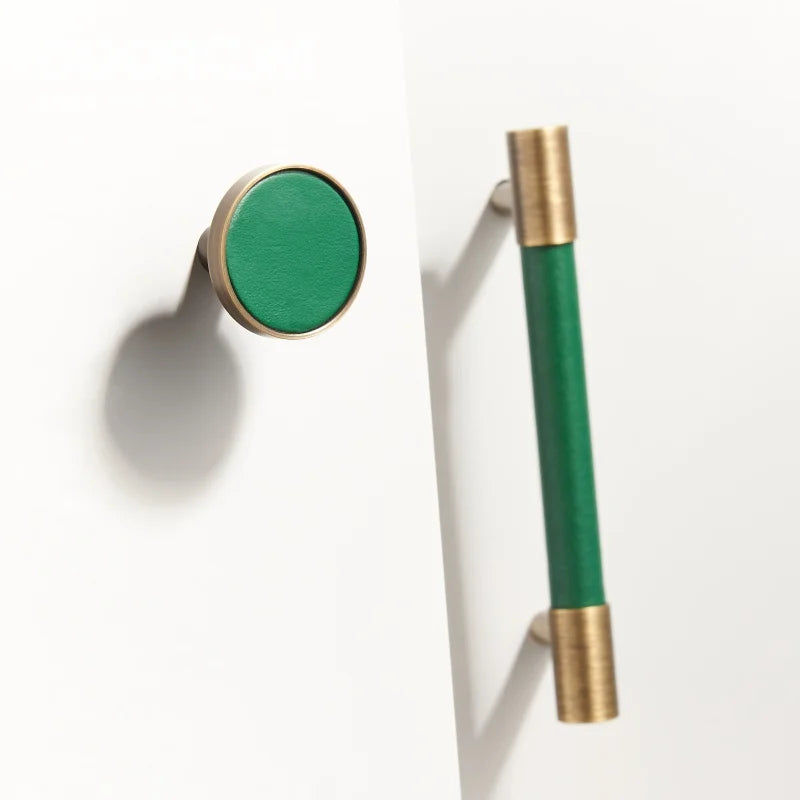 Dooroom brass furniture handles with green leather detail, including a round knob and cylindrical pull, suitable for cupboards and cabinets.