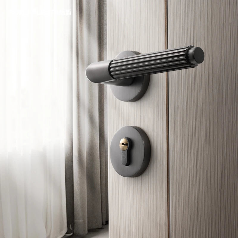 Black-gray brushed wire bedroom door lock on a wooden door with natural light.