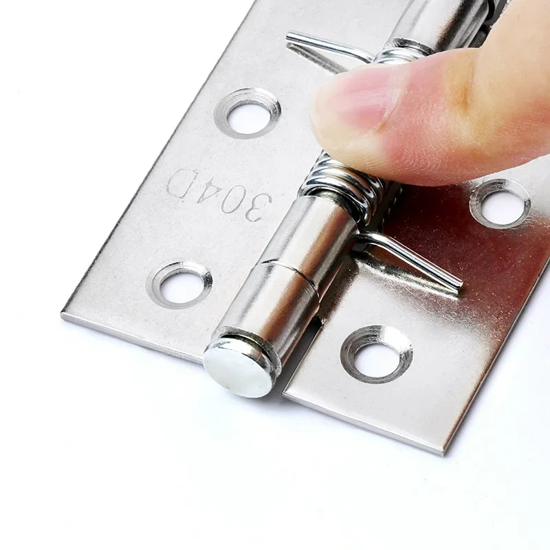 Stainless steel cross hinge with automatic rebound and spring mechanism for cabinets, shown with a finger pressing to demonstrate functionality.