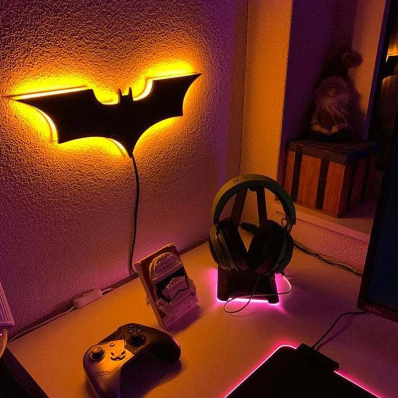 Modern Batman logo-shaped wall lamp with 16-color LED lighting, remote control, and 2-meter cable, mounted on a wooden background.