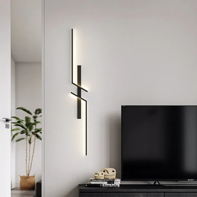 Modern LED wall lamp with minimalist design and black finish, mounted on a grey wall beside a TV console in a stylish living room.