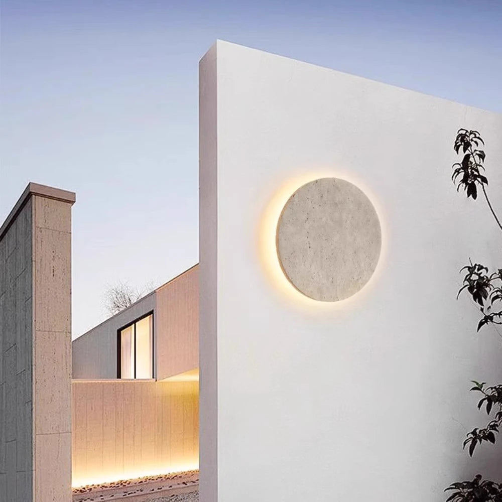 Outdoor waterproof stone wall light with warm yellow glow on a modern courtyard villa exterior.