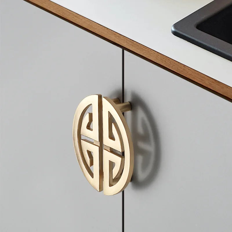 Gold Chinese style cabinet handle on a light gray cabinet door