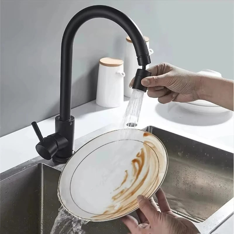Premium rotatable kitchen faucet in matte black with pull-out spray head, shown in use cleaning a plate over a stainless-steel sink.