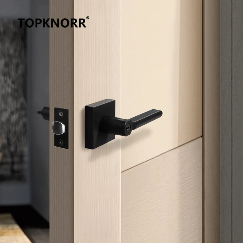 American bathroom door lock with keyless three-pole mechanism and black handle on light wood door.