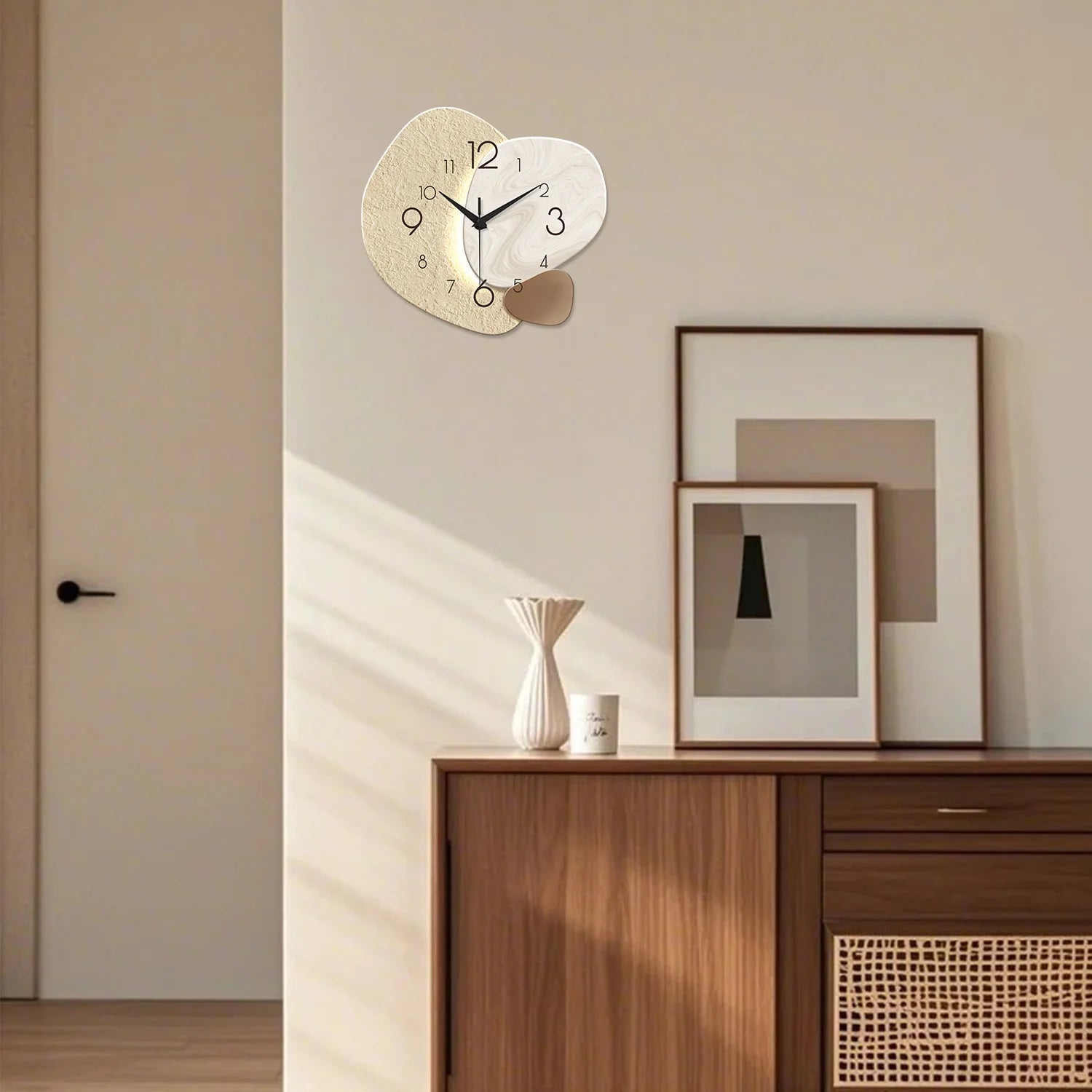 Modern abstract wall clock with silent quartz movement, featuring a beige and white design, against a minimalist living room setting.