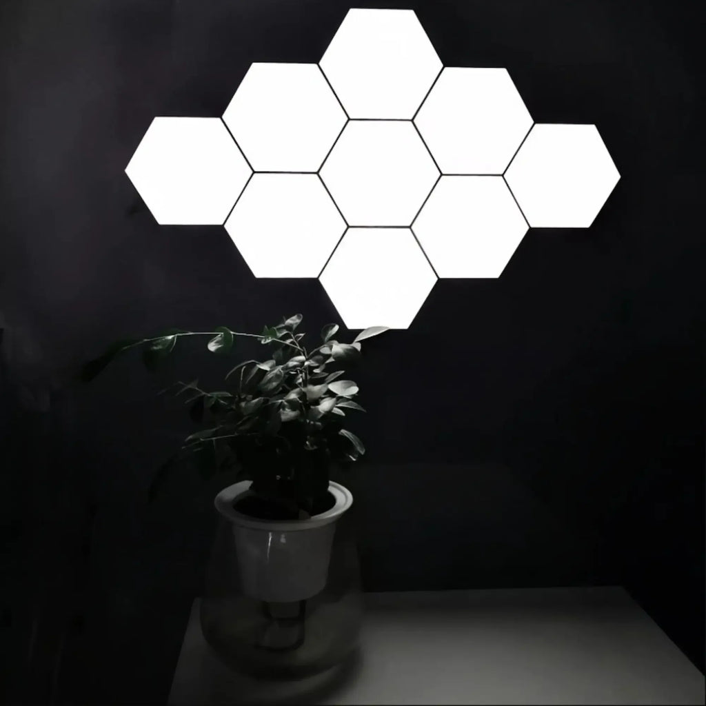 Hexagonal touch LED wall light emitting neutral white light in a 6-pack configuration, mounted on a dark wall above a potted plant.